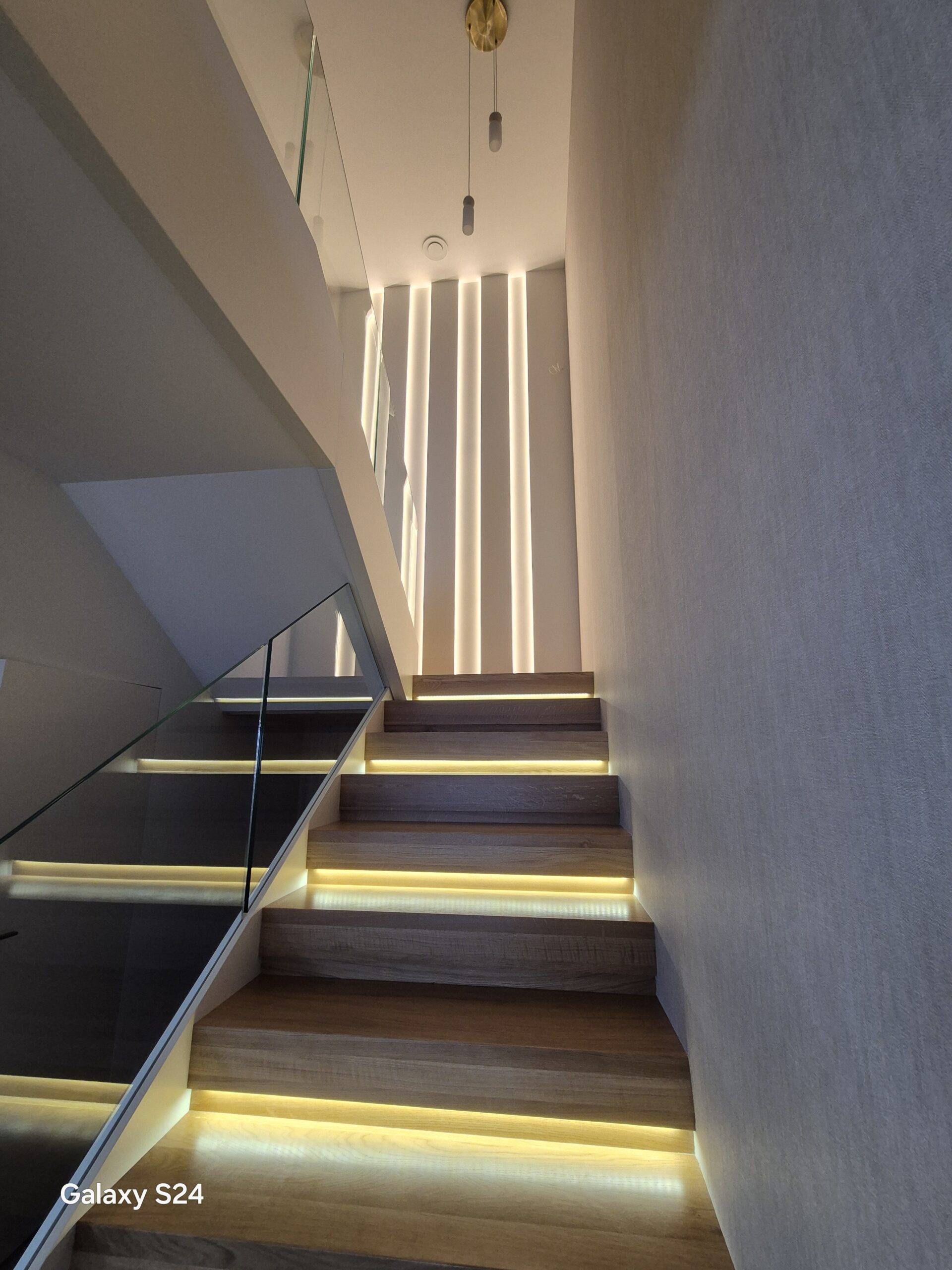 Nowoczesne schody z podświetleniem LED, szklaną balustradą i dekoracyjną ścianą świetlną – wykończenie wnętrz DECO MAX Rzeszów